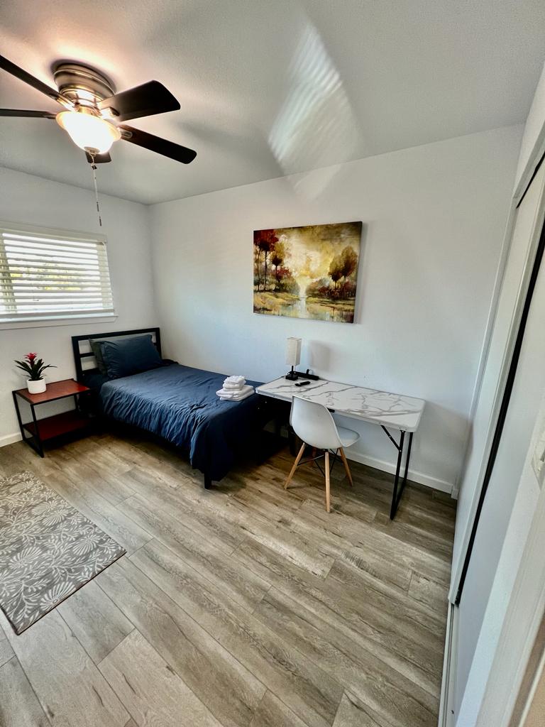 A bedroom with a bed, desk and chair.