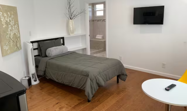 A bedroom with a bed, tv and table.