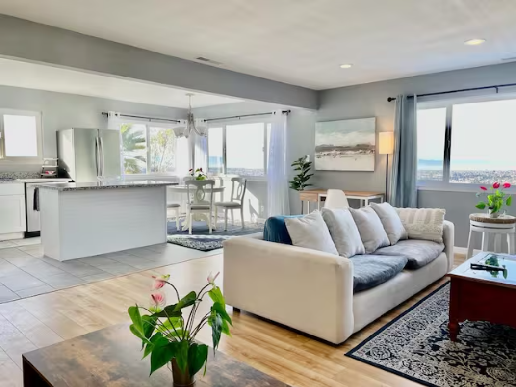 A living room with white furniture and a large open floor plan.