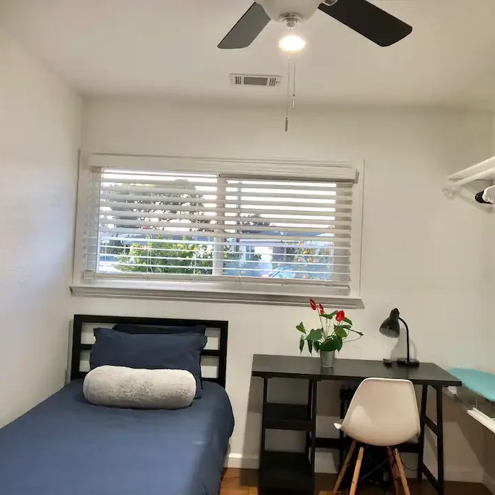 A bedroom with a desk and chair in it