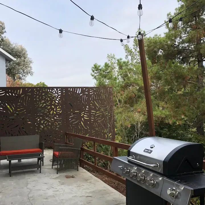 A grill on the patio of an outdoor room.