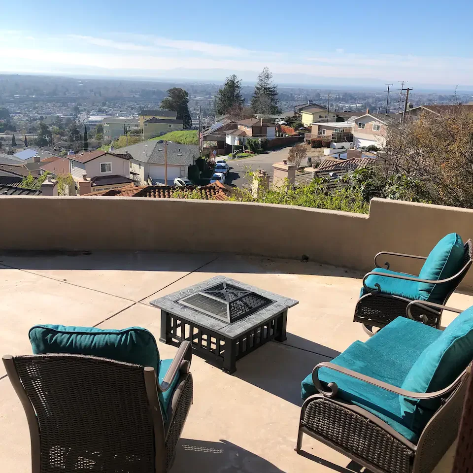 A patio with chairs and fire pit overlooking the city.