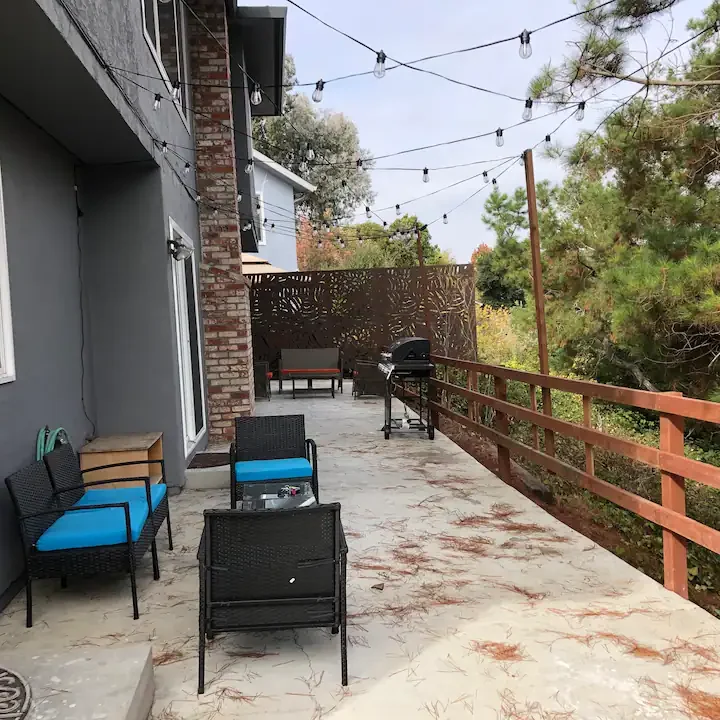 A patio with chairs and tables on the side of the house.